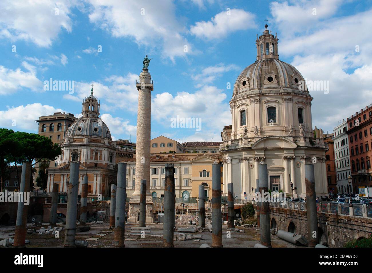 Blick auf die Trajanssäule, mit dem Petersdom auf der rechten Seite, in Rom, Italien. Die Säule ist berühmt für ihr spiralförmiges Relief zum Gedenken an Kaiser Trajans Sieg in den Dacianischen Kriegen. Stockfoto