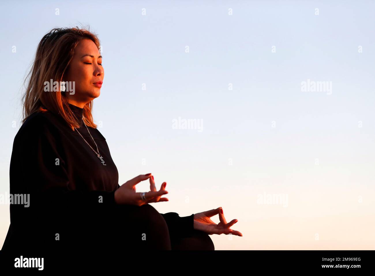 Yoga-Praktizierende Frau am Meer vor Sonnenuntergang als Konzept für Ruhe und Entspannung. Stockfoto