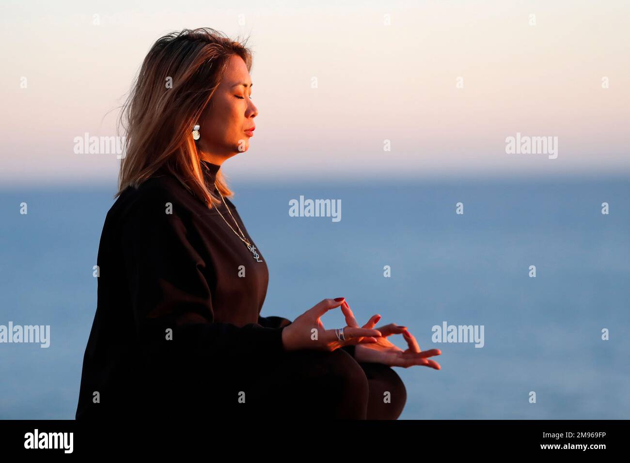 Yoga-Praktizierende Frau am Meer vor Sonnenuntergang als Konzept für Ruhe und Entspannung. Stockfoto