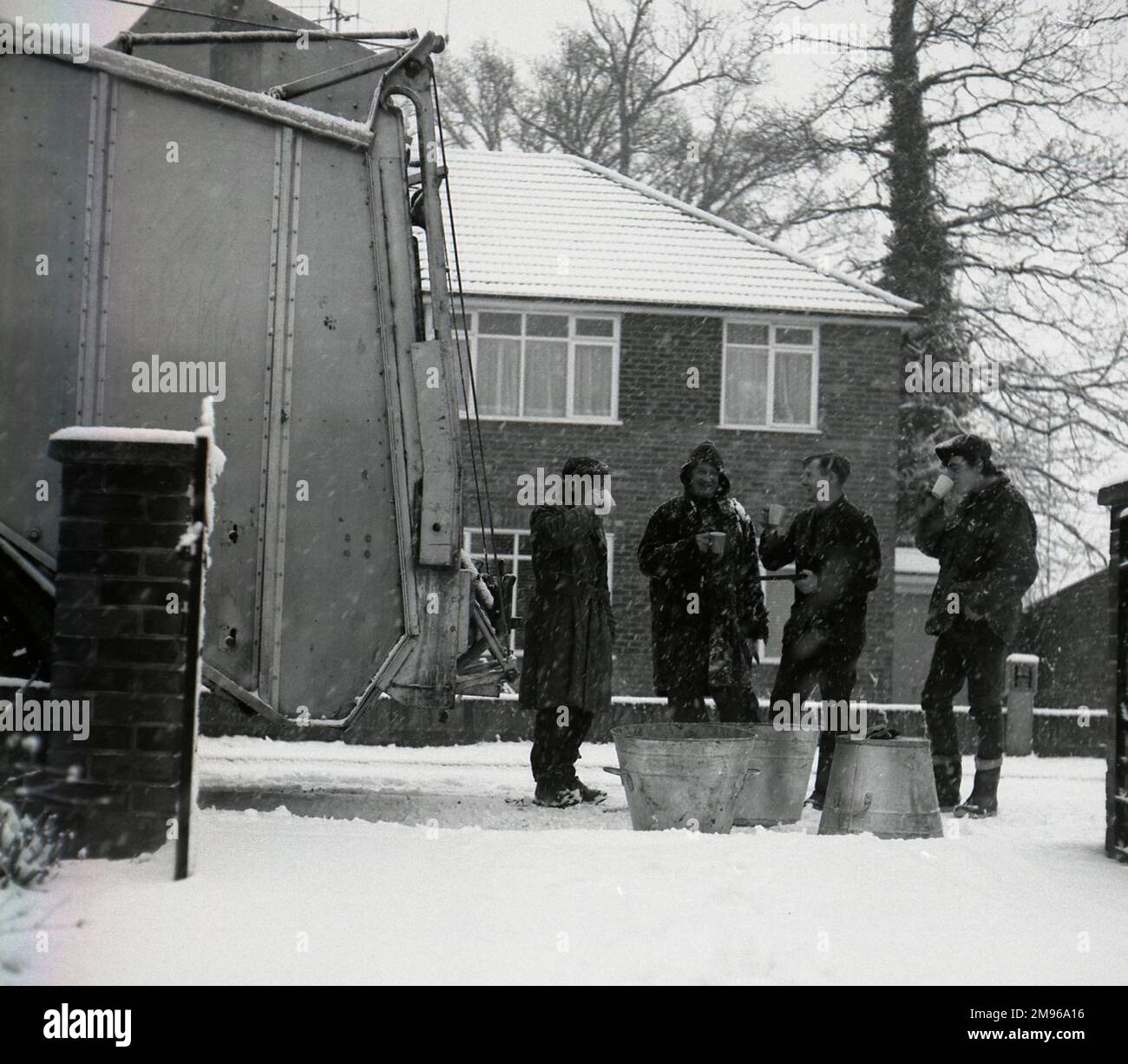 Vier Arbeiter halten an einem verschneiten Wintertag für eine Tasse Tee zur Begrüßung. (1 von 2) Stockfoto