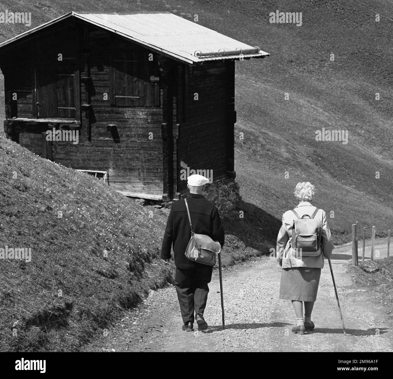 Ein älteres Ehepaar, das auf dem Land spazieren geht, eine abfallende Strecke hinunter. Stockfoto