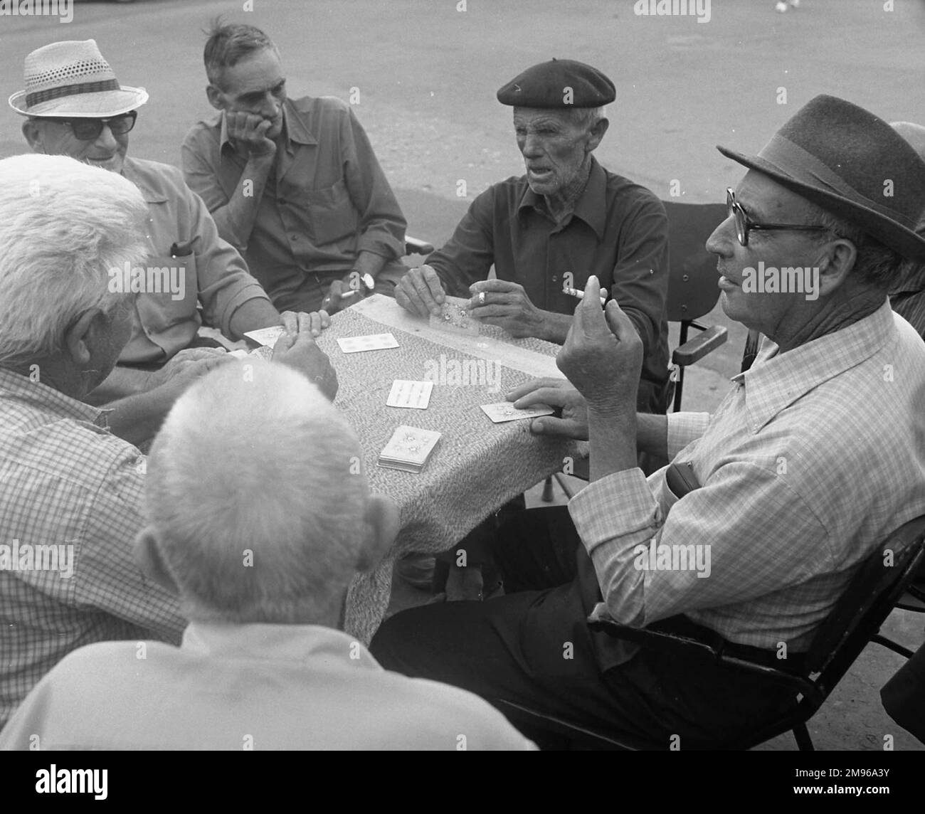 Sechs Männer spielen ein Kartenspiel an einem Tisch auf der Straße. Stockfoto