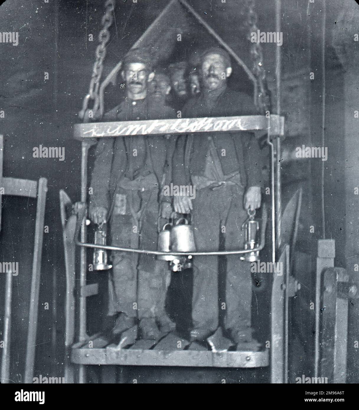 Mehrere Bergleute mit geschwärzten Gesichtern stehen am Ende ihrer Schicht in einem Kohlebergwerk in Südwales im Schachtlift. Stockfoto