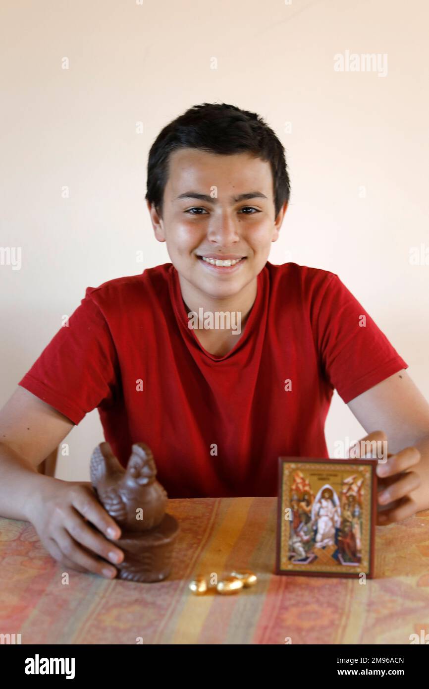 15-jähriger Junge mit einer Osterschokoladenhuhn und einer christlichen Ikone in Eure, Frankreich Stockfoto