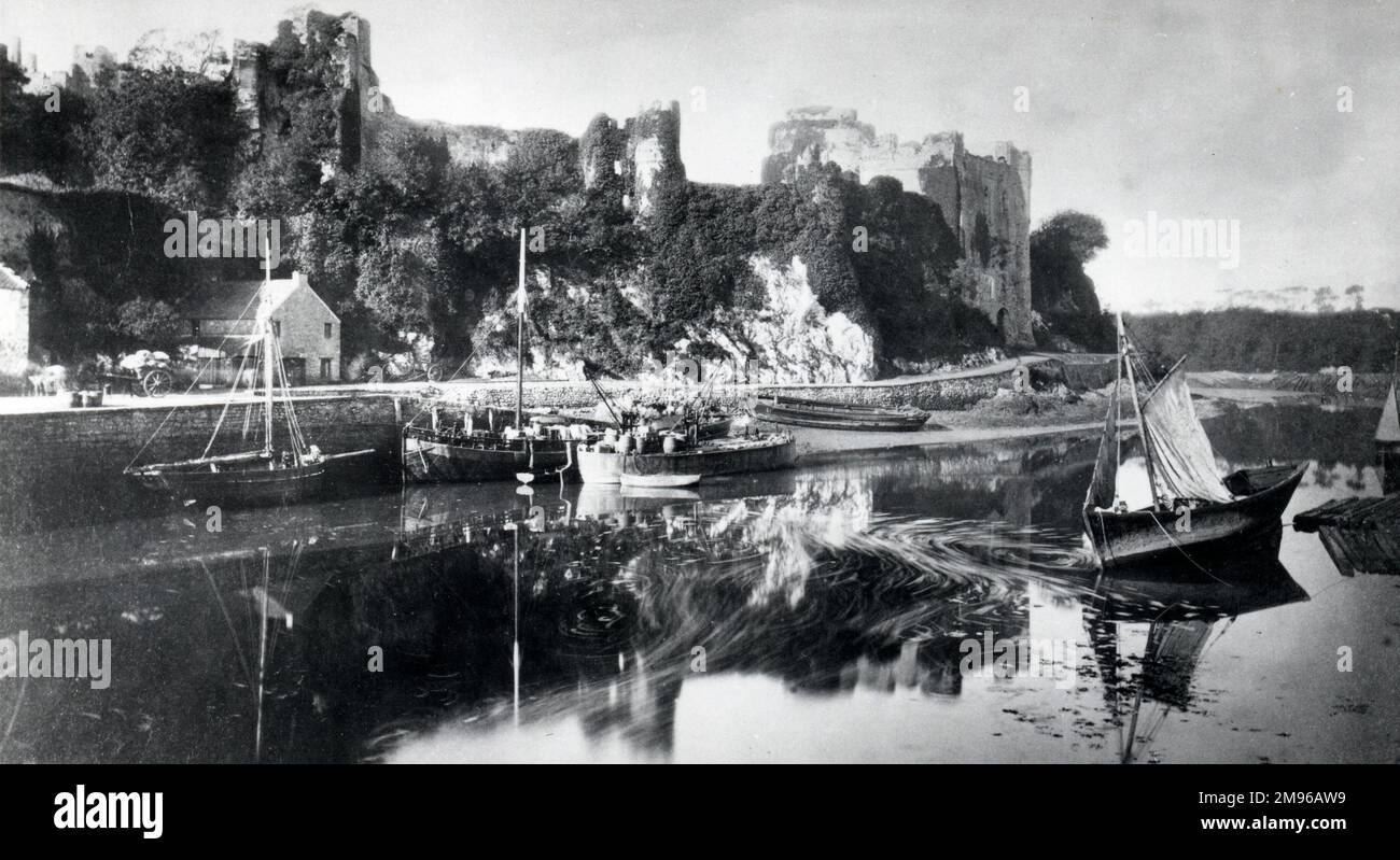 Blick auf die efeubedeckten Ruinen von Pembroke Castle in Pembrokeshire, West Wales, von der anderen Seite des Wassers aus. Das Schloss stammt aus dem 11. Jahrhundert. Seit der Aufnahme dieses Fotos wurden umfangreiche Renovierungsarbeiten durchgeführt. Stockfoto