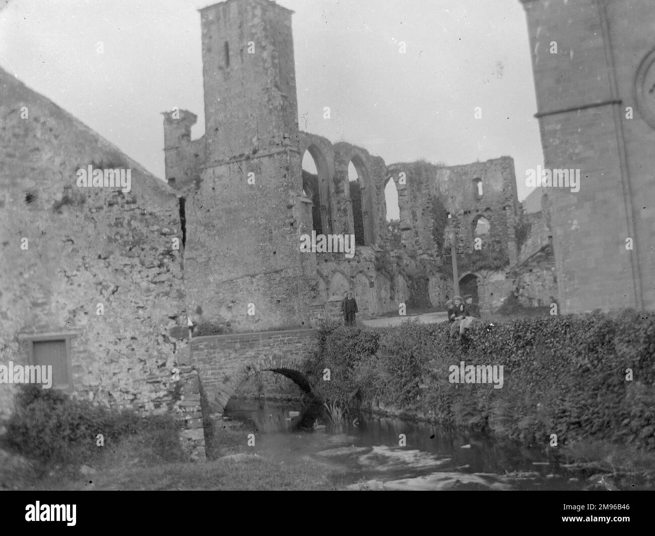 Teil der Ruinen des mittelalterlichen Bischofspalastes, St. David's, Pembrokeshire, Dyfed, Südwales, Mit Bach und Brücke daneben. Einige Teile des Gebäudes stammen aus dem 12. Jahrhundert, aber die meisten Arbeiten wurden im 14. Jahrhundert ausgeführt. Stockfoto