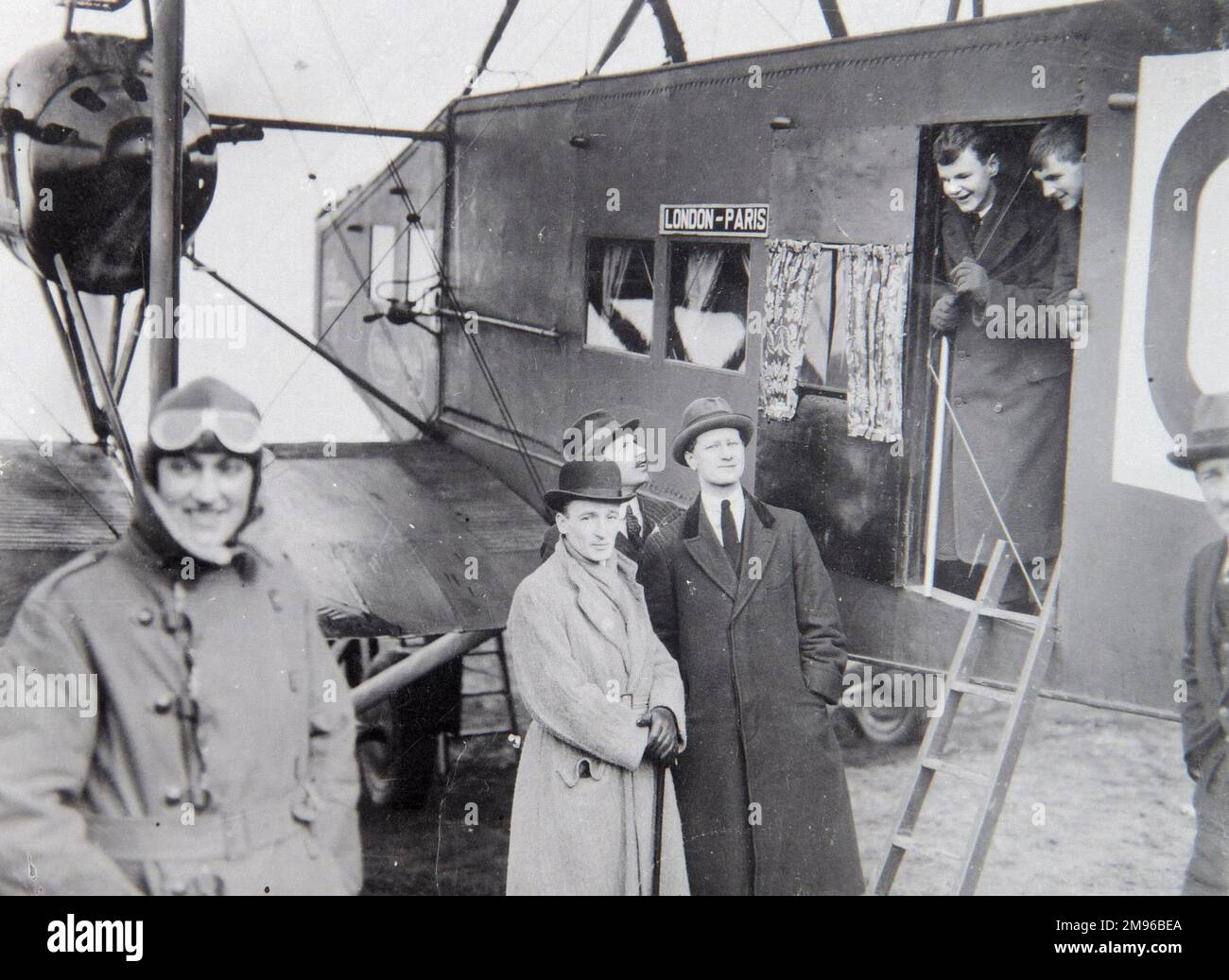 Eine Gruppe von Passagieren mit einem Flugzeug, das sie auf einem Flug von London nach Paris in den frühen Tagen der Luftfahrt mitnimmt. Der Pilot steht links, mit der Schutzbrille auf der Stirn. Das Flugzeug ist eine Handley Page O/400, die als Flugzeug für die Beförderung von Würdenträgern zwischen London und Paris für die Verhandlungen über den Vertrag von Versailles umgebaut wurde. Stockfoto