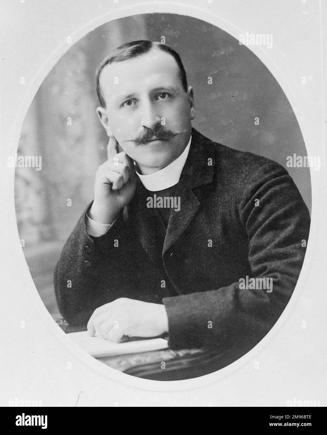 Ein edwardianischer Pfarrer in einem ovalen Kopf- und Schulterporträt, Mid Wales. Er sitzt an einem Schreibtisch mit einem Buch unter der Hand. Stockfoto