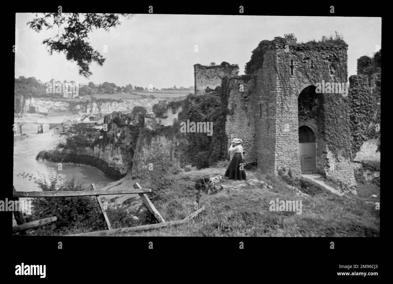 Edwardianische Frau im Schloss Chepstow, mit Blick auf den Fluss Wye in Gwent (ehemals Monmouthshire), Wales. Der Bau begann im 11. Jahrhundert und ist damit die älteste noch existierende Steinbefestigung in Großbritannien. Stockfoto