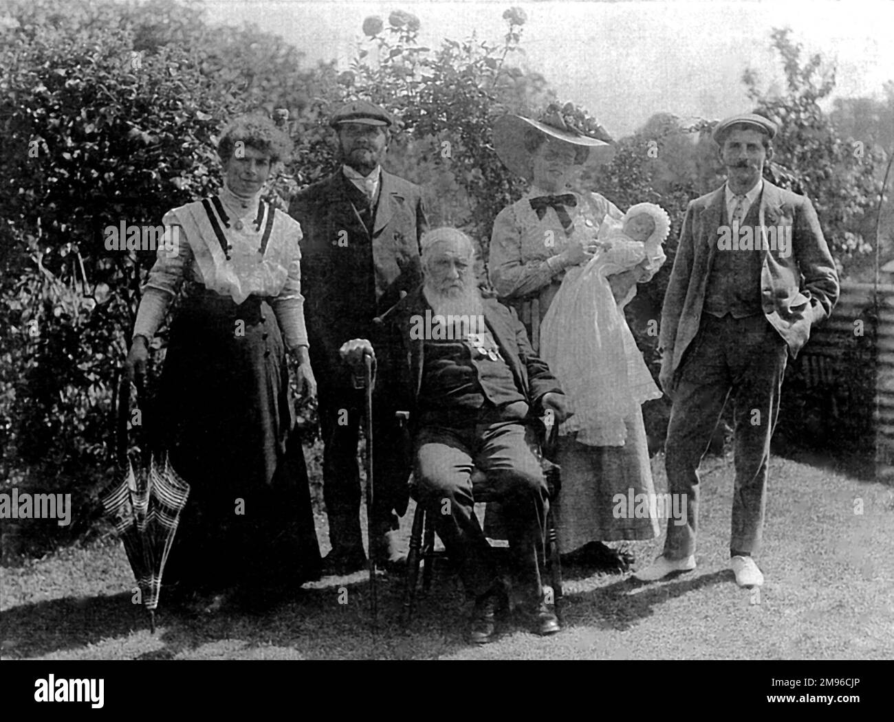 Mitglieder der Malby-Familie (fünf Erwachsene und ein Baby) posieren für ein Gruppenfoto in ihrem Garten in Woodford, Essex. Ganz rechts befindet sich Reginald Malby (1882-1924), offizieller Fotograf der Royal Horticultural Society. Neben ihm steht seine Frau Eleanor (1886-1956) und in der Mitte sitzt Reginalds Vater Henry Thomas Malby (1845-1928), Fotograf und Künstler. Stockfoto