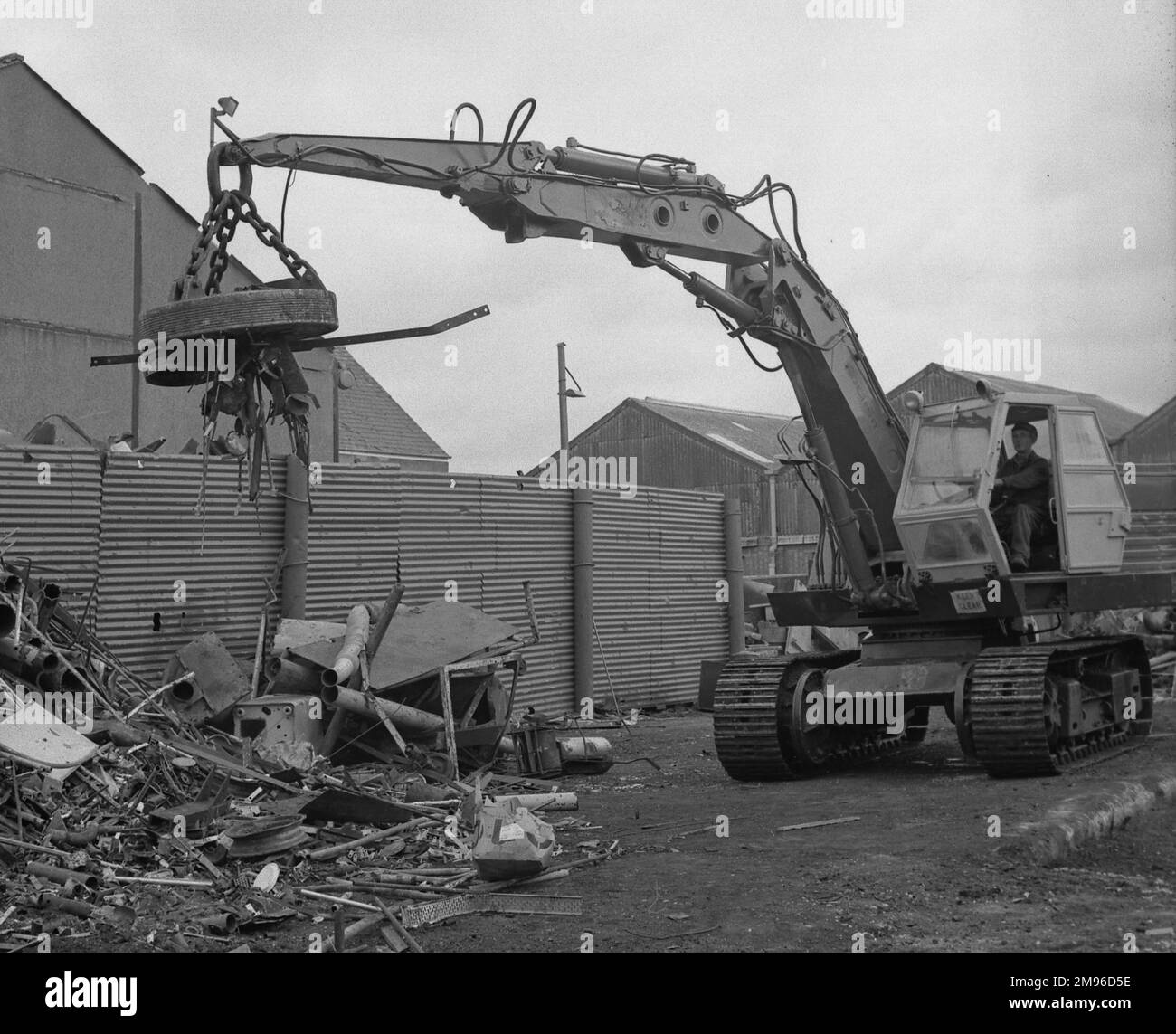 Szene auf einem Schrottplatz, wo ein Magnetkran verstreute Metallstücke aufnimmt. Stockfoto