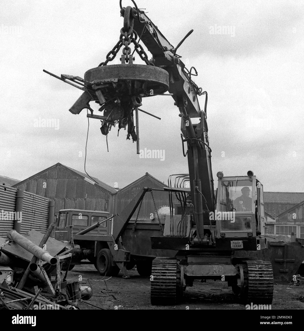 Szene auf einem Schrottplatz, wo ein Magnetkran verstreute Metallstücke aufnimmt. Stockfoto