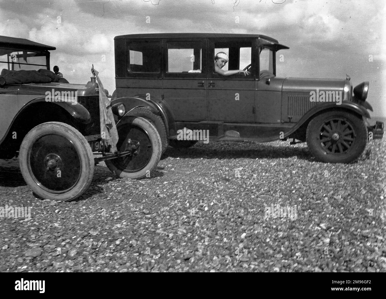 Eine Frau, die in einem Auto auf Kieselboden sitzt. Stockfoto
