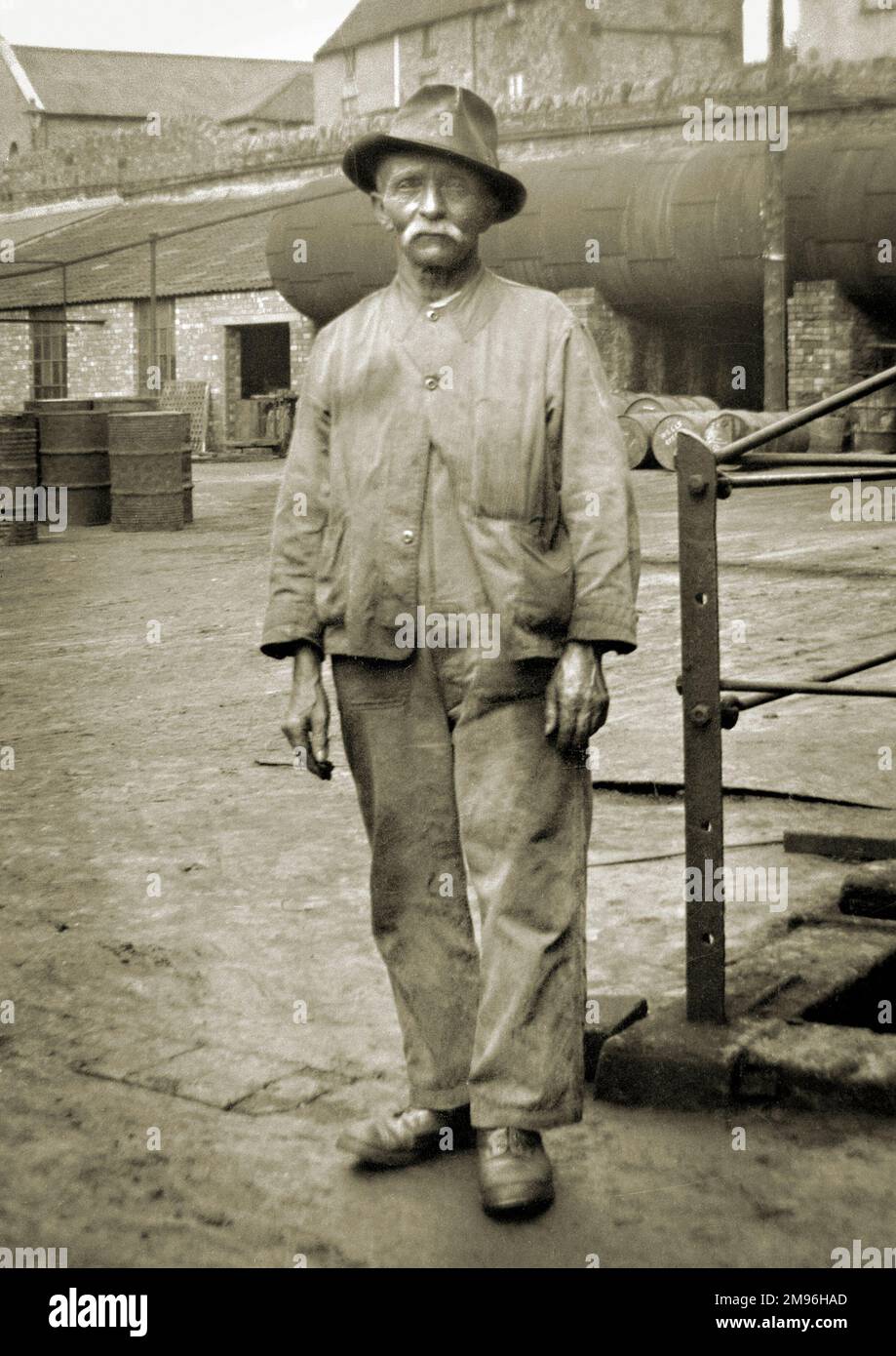 Ein älterer Arbeiter, der in einem Hof steht. Stockfoto