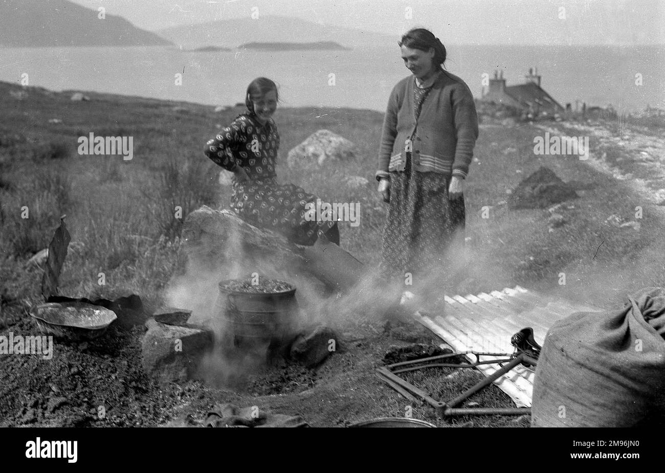 Zwei Frauen mit einem rauchenden Brazier in einer ländlichen Landschaft auf der Insel Harris, Schottland. Stockfoto