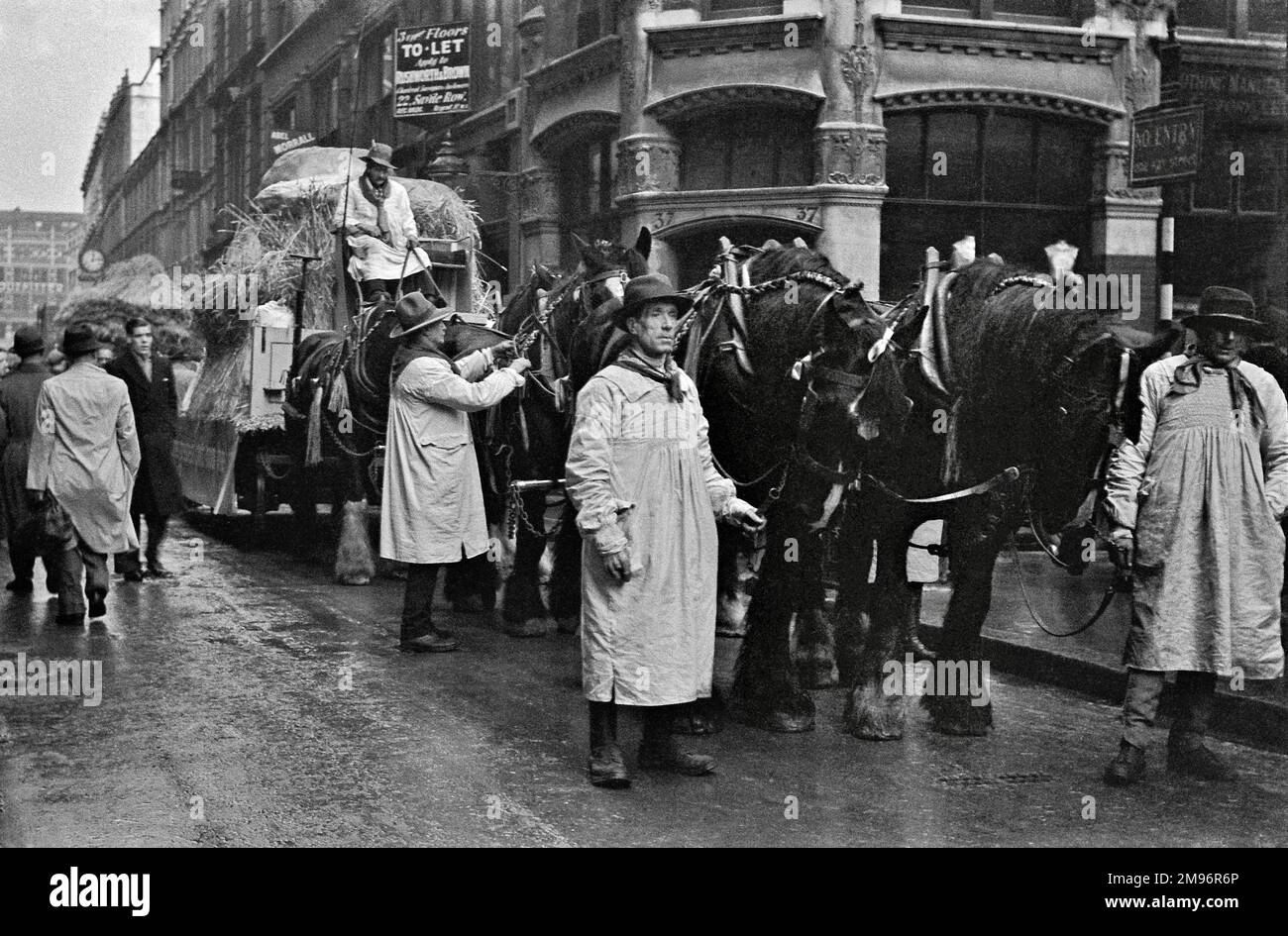Landsleute in Kittel, mit haycart und Pferden, in einer Londoner Straße. Stockfoto