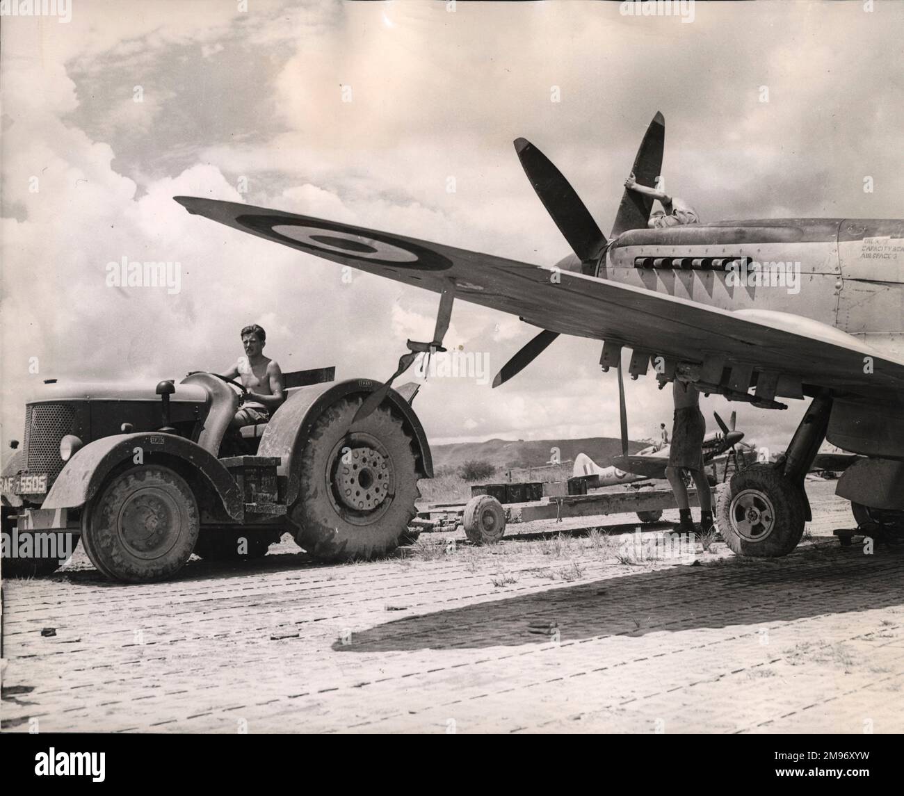 Der Blick unter dem Flügel eines Supermarine Spitfire FRXVIII am Kuala Lumpur Airport, Malaya, während ein Munitionswagen ankommt, während er sich auf einen Angriff der 60 Fighter Group gegen die Guerillas vorbereitet. Juni 1950. Stockfoto