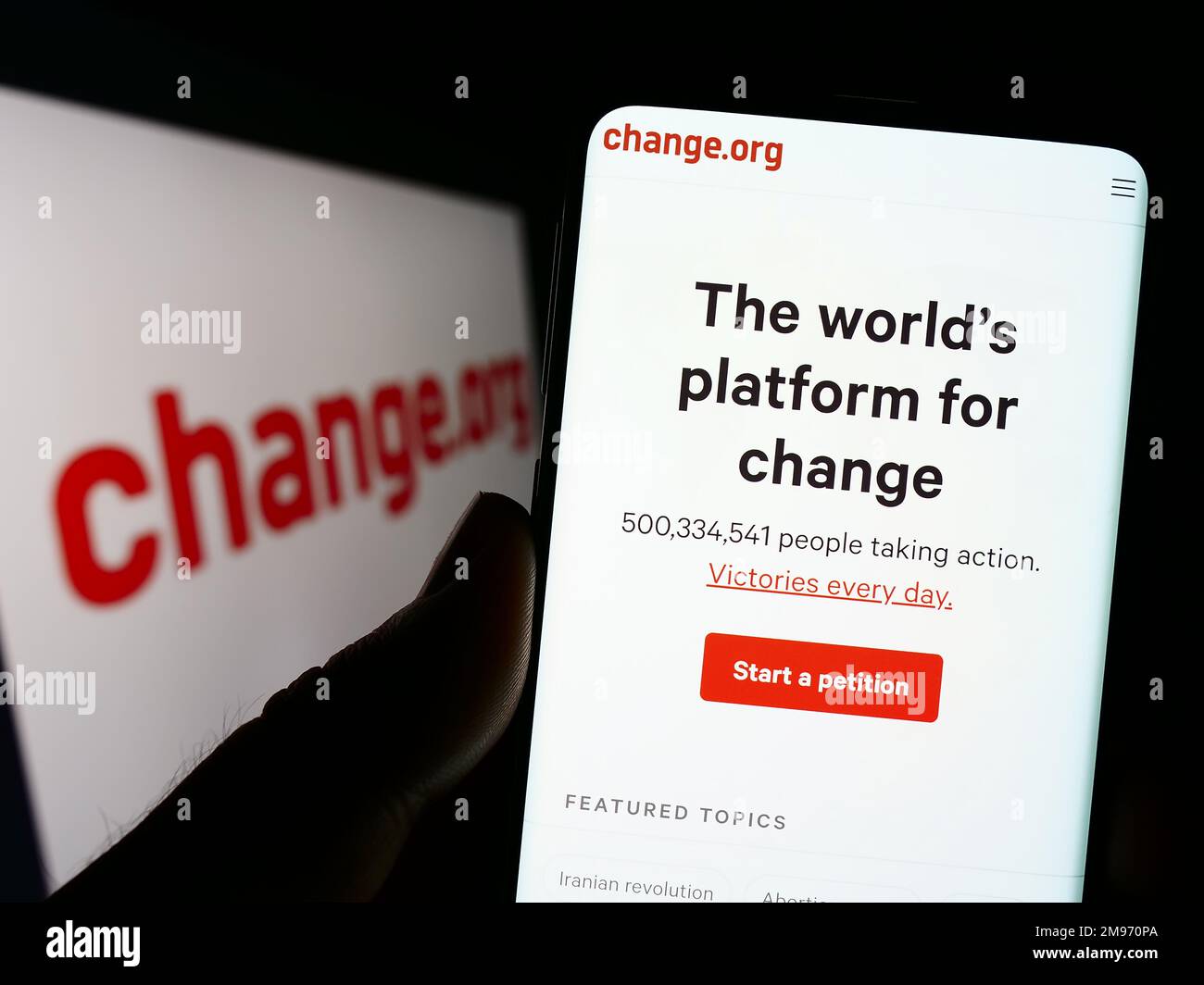 Person, die ein Mobiltelefon mit einer Website der US-PBC-Plattform Change.org auf dem Bildschirm vor dem Logo hält. Konzentrieren Sie sich auf die Mitte des Telefondisplays. Stockfoto