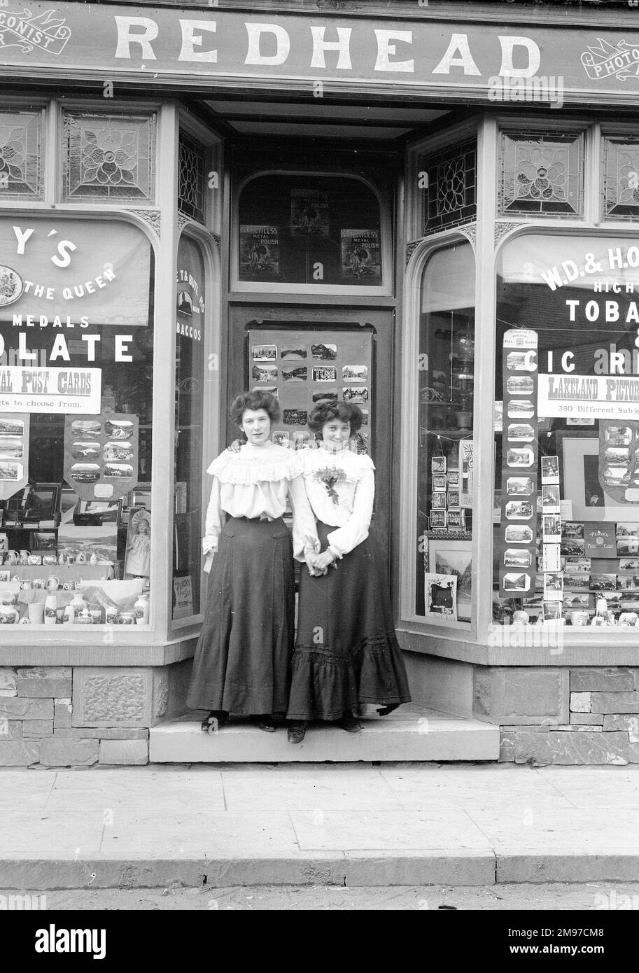 Rothaarig's Laden, Coniston, mit Annie und Kate in der Tür. Sie arbeiteten in dem Laden, der sich in der Yewdale Road Coniston befindet und heute noch als Zeitungskiosk/Souvenirladen geführt wird. Stockfoto