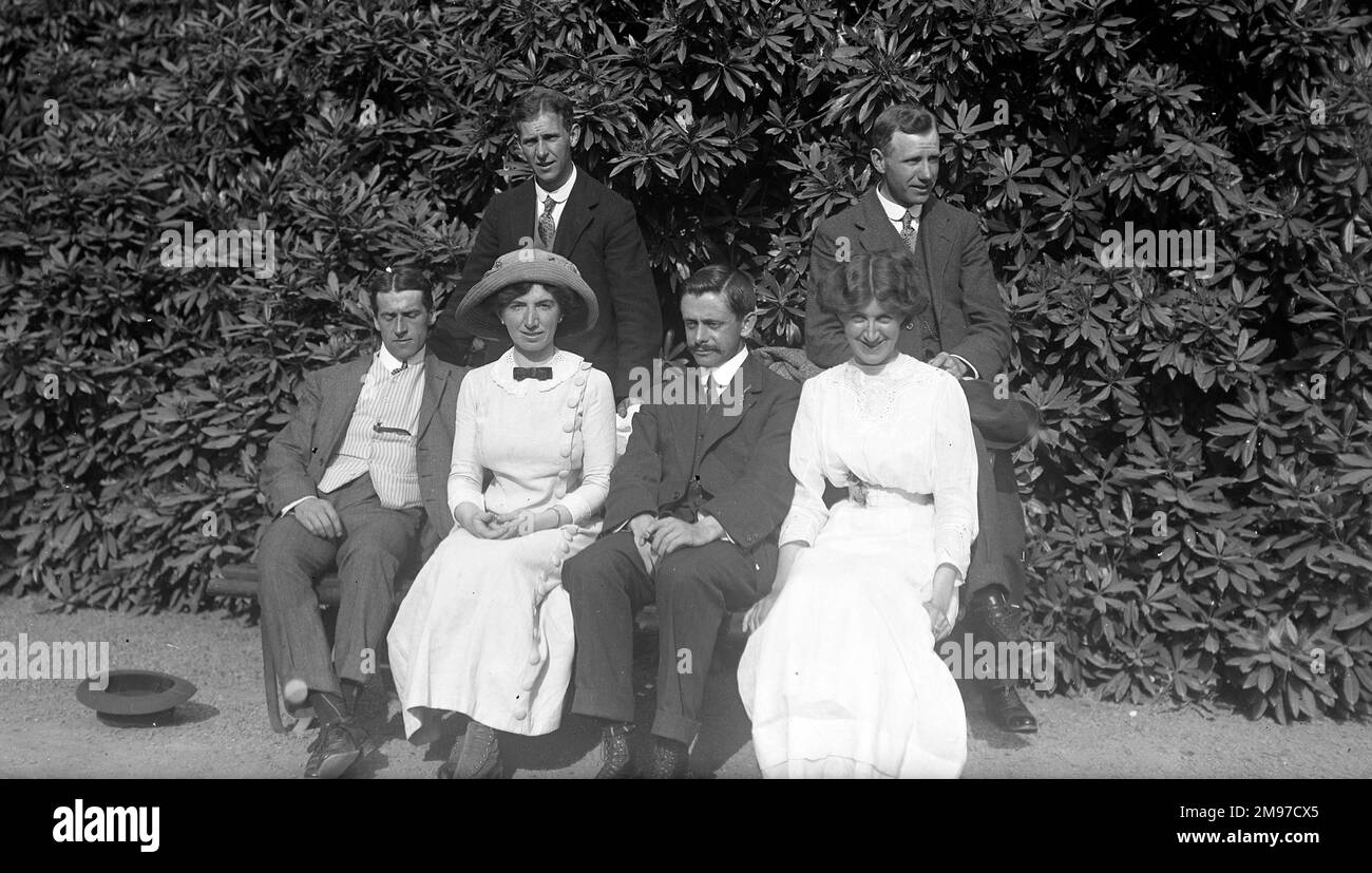 Gruppe in Gärten, die edwardianische Mode zeigen - der Fotograf Ernest Battersby sitzt zwischen den beiden Damen Stockfoto
