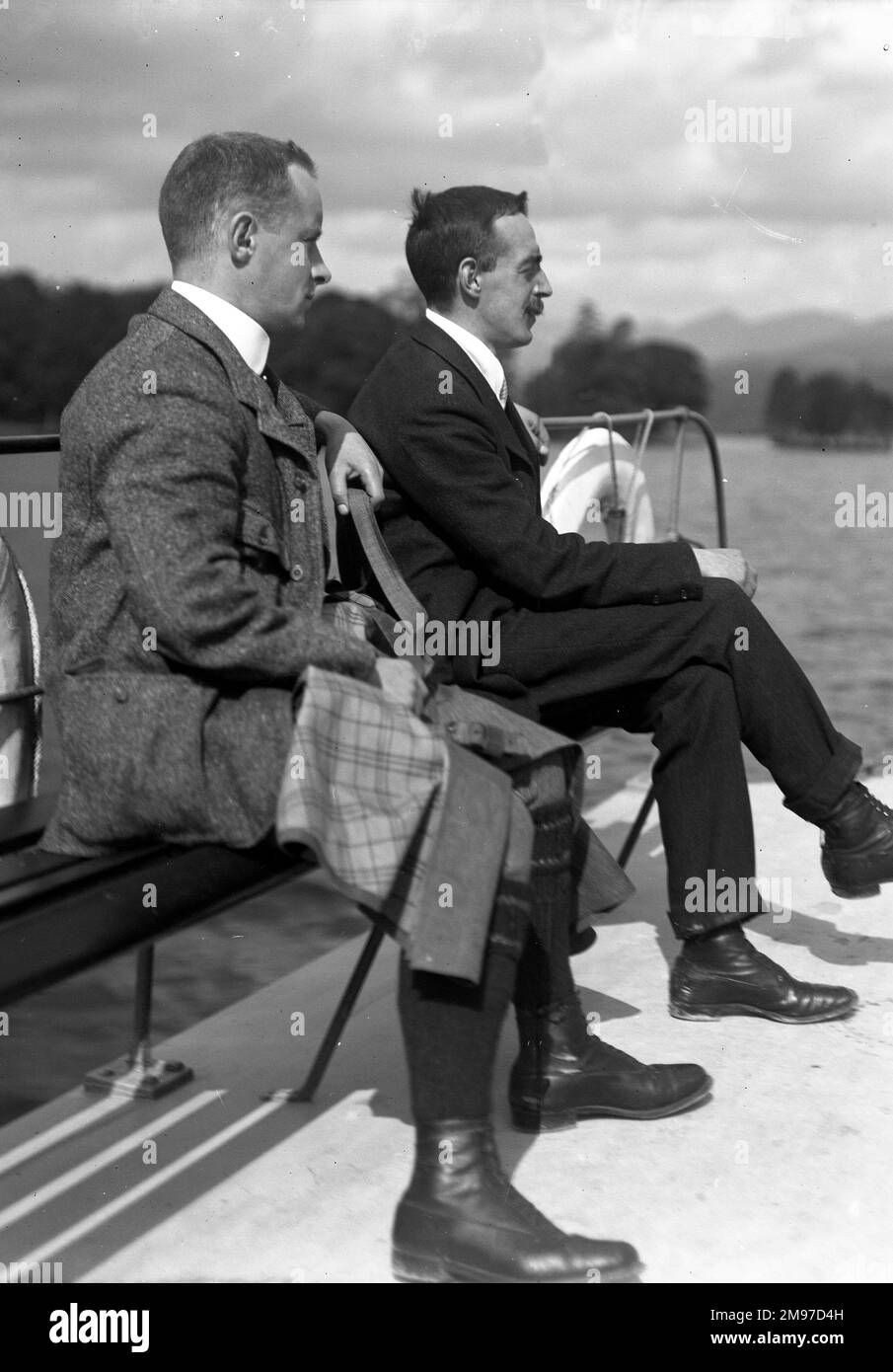 Edwardianische Gentlemen auf einem Boot im Lake District, vermutlich Coniston, zeigen eine entspannte und raffinierte Atmosphäre mit zeitgenössischem Stil. Stockfoto