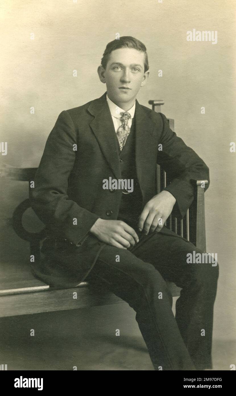 Ein klug gekleideter Junge, der auf einer Bank sitzt. Stockfoto