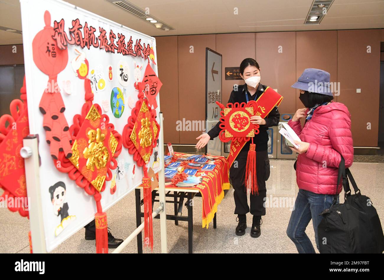 (230117) -- PEKING, 17. Januar 2023 (Xinhua) -- Ein Passagier (R) wird angeboten, kleine Geschenke zu sammeln, bevor er den Flug CZ309 am Peking Daxing International Airport in Peking, Hauptstadt von China, am 17. Januar 2023 antritt. Mit dem Start des CZ309-Fluges nach Hongkong nahm der Internationale Flughafen Peking Daxing am Dienstag den Betrieb internationaler Passagierflüge wieder auf, nachdem China seine Politik zur Prävention und Bekämpfung von COVID-19-Epidemien kontinuierlich optimiert hatte. Als neuester Flughafen Pekings wurde der Peking Daxing International Airport am 25. September 2019 in Betrieb genommen. Ab dem 14. März 2020 ist die Ai Stockfoto