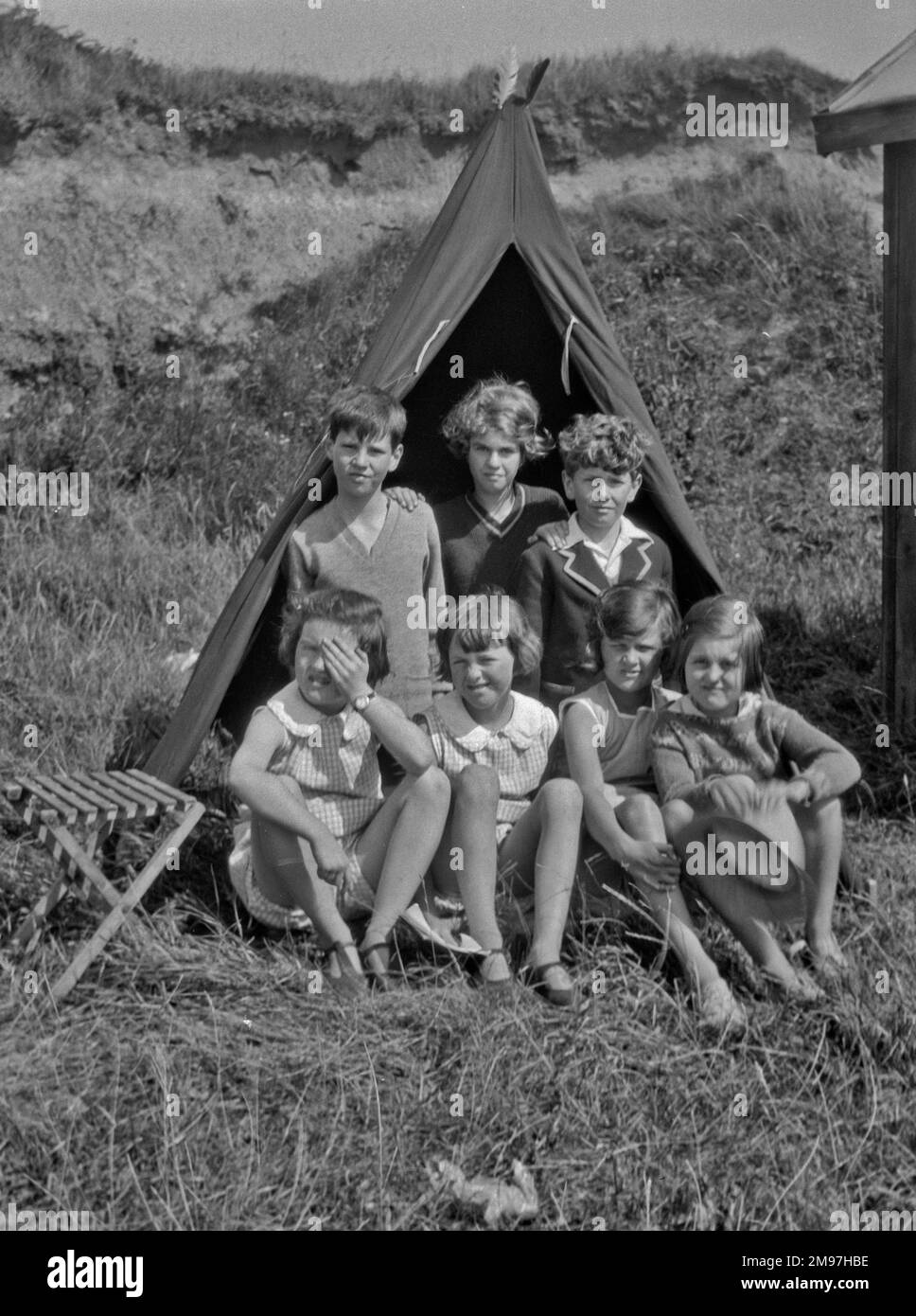 Eine Gruppe von sieben Kindern, die auf einem Feld campen. Stockfoto