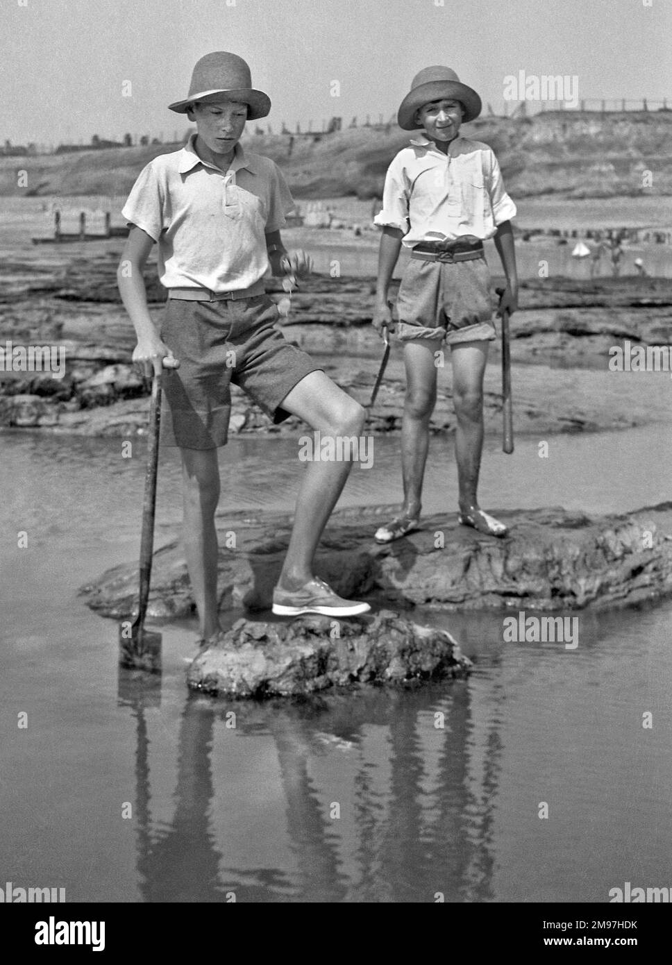 Zwei Jungs mit Pik, die Felsenbecken am Meer erkunden. Stockfoto