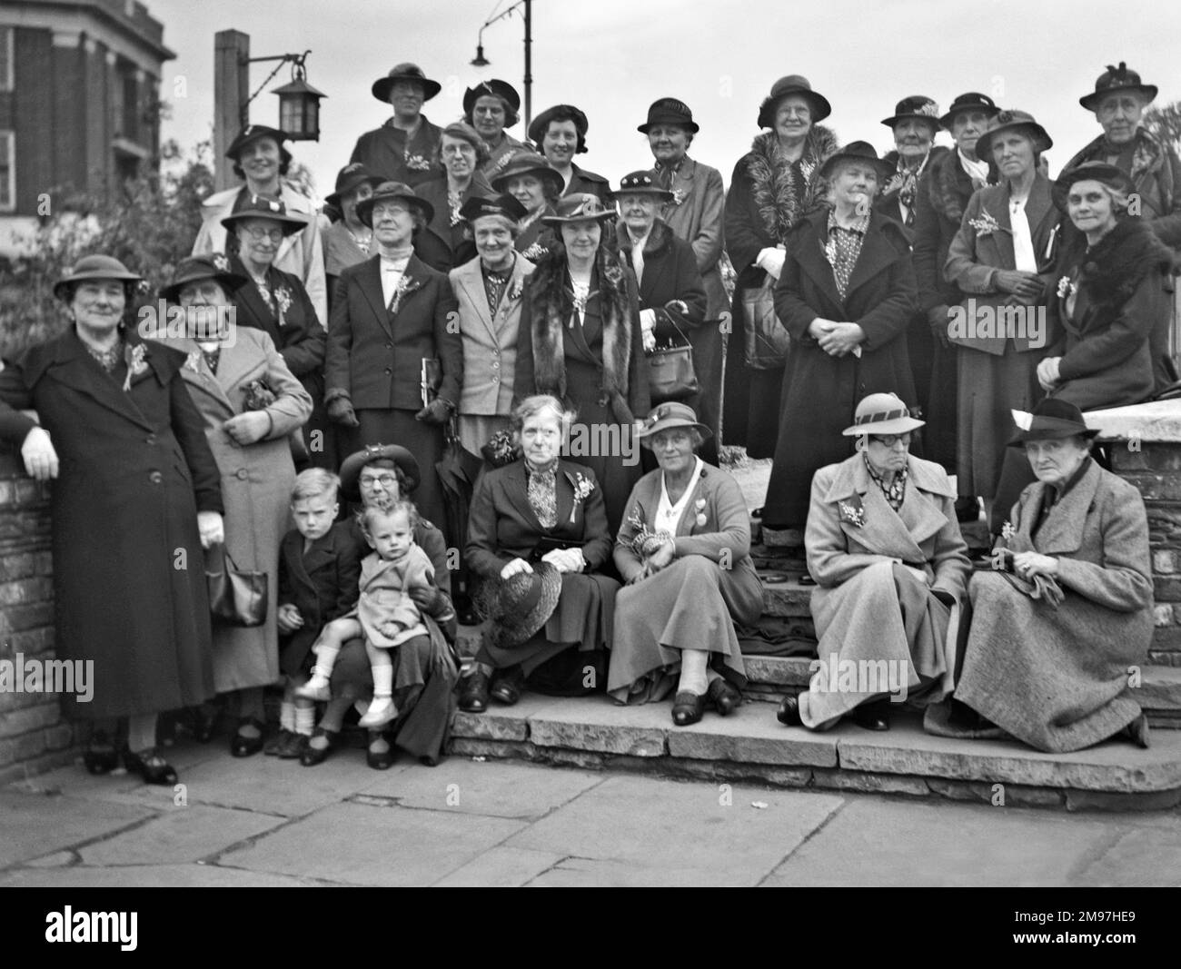 Gruppenfoto von Frauen mittleren Alters in Hüten und Mänteln, mit zwei kleinen Kindern. Stockfoto