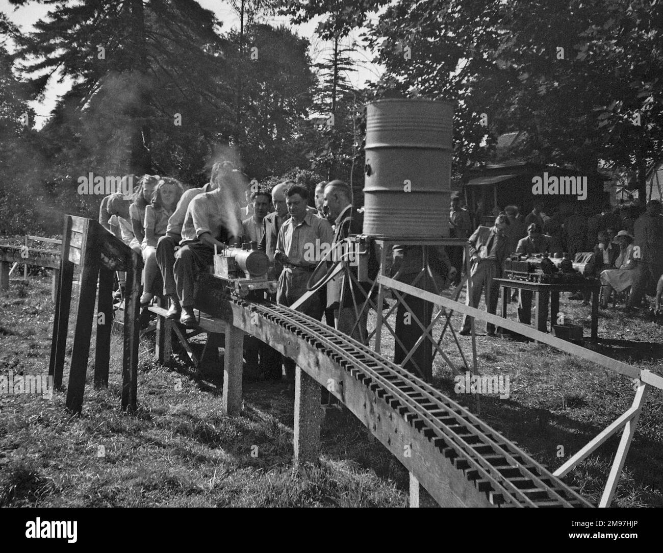 Leute mit einer Miniatur-Dampfeisenbahn auf einer erhöhten Strecke. Stockfoto