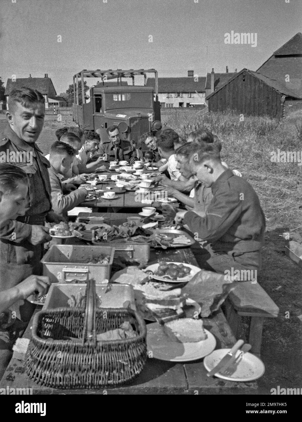Soldaten essen an zwei langen Tischen im Freien in einem Lager. Stockfoto