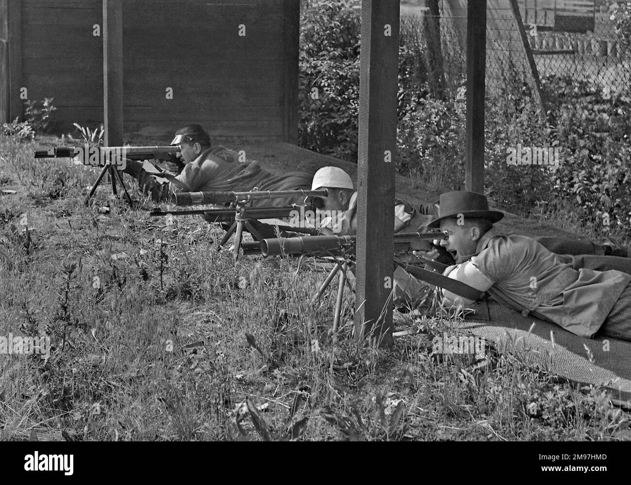 Drei Männer auf einem Schießstand, mit Gewehren und Teleskopen auf Stativen. Stockfoto