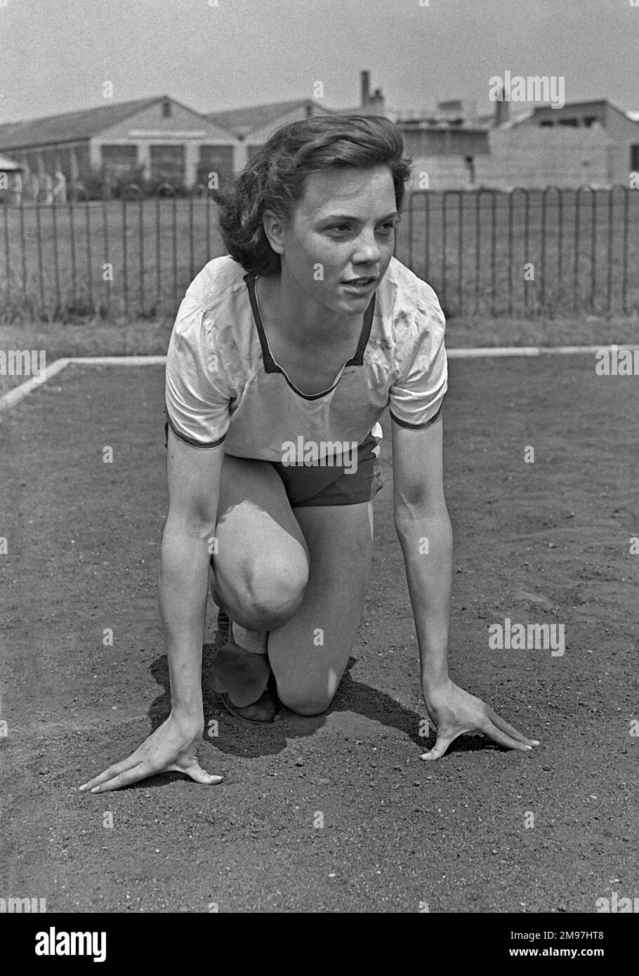 Eine junge Sportlerin in Startposition auf einer Sportstrecke. Stockfoto