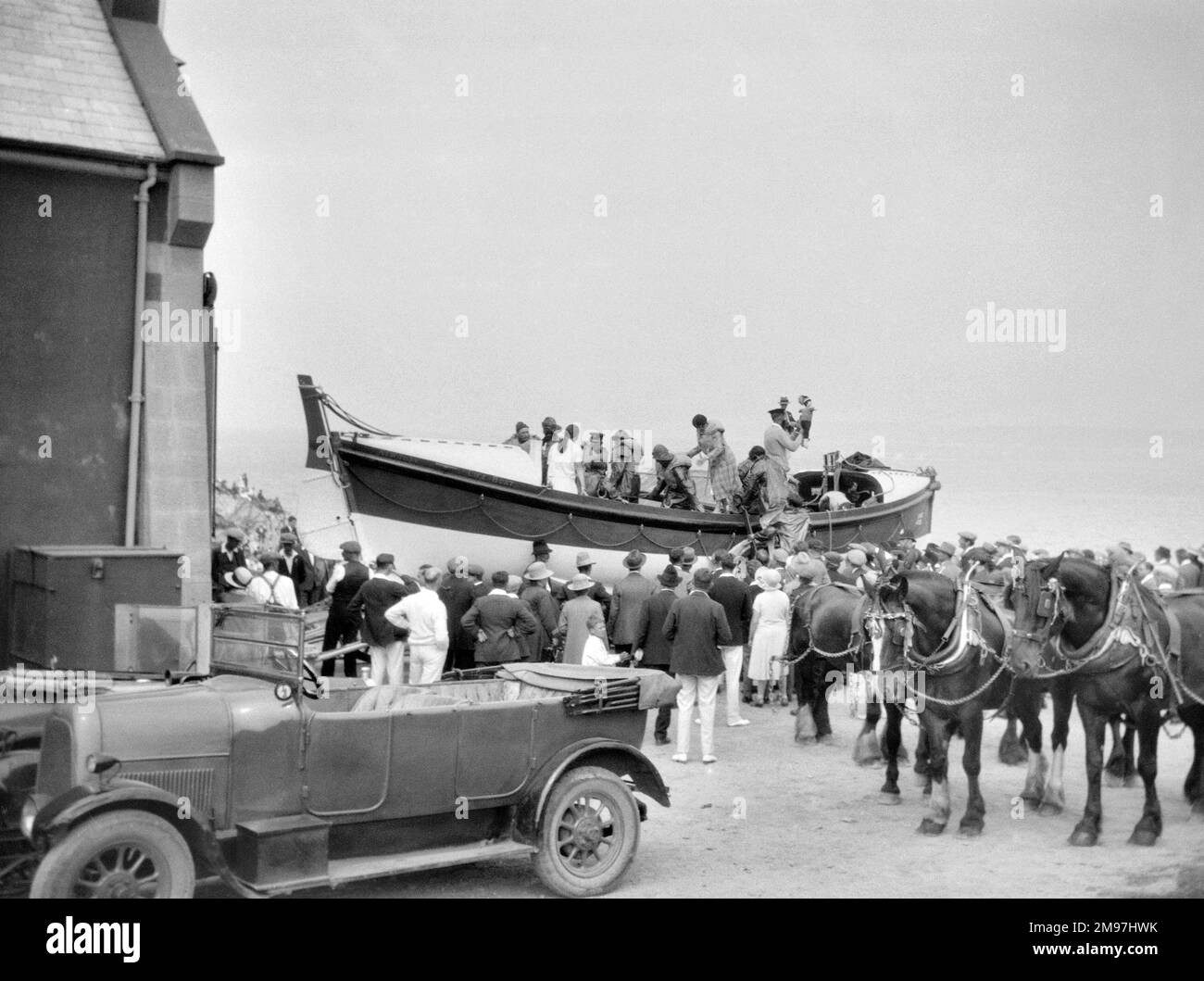 Menschen in und um ein Rettungsboot, mit Pferden und einem Auto im Vordergrund. Stockfoto