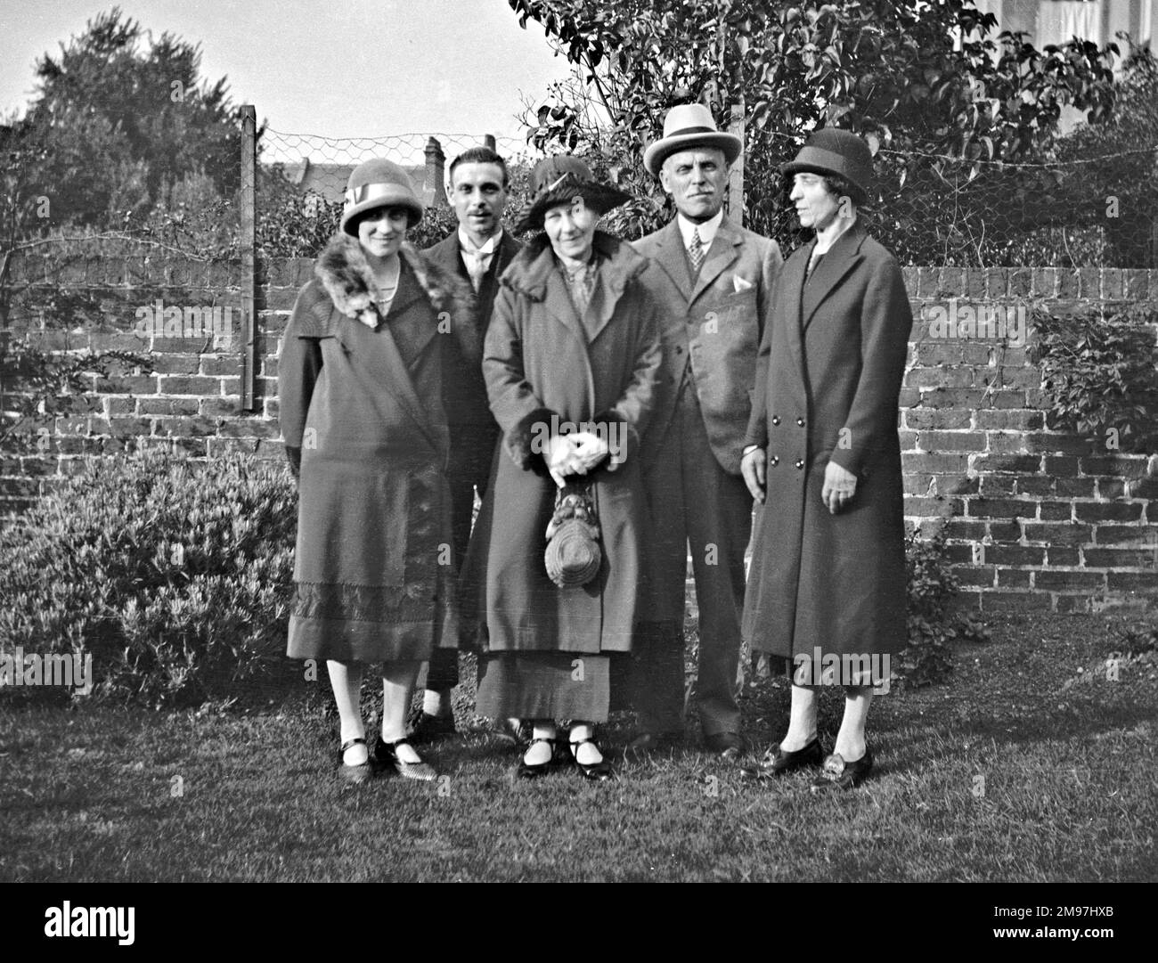 Eine fünfköpfige Familiengruppe, die für ihr Foto in einem Garten posiert. Stockfoto