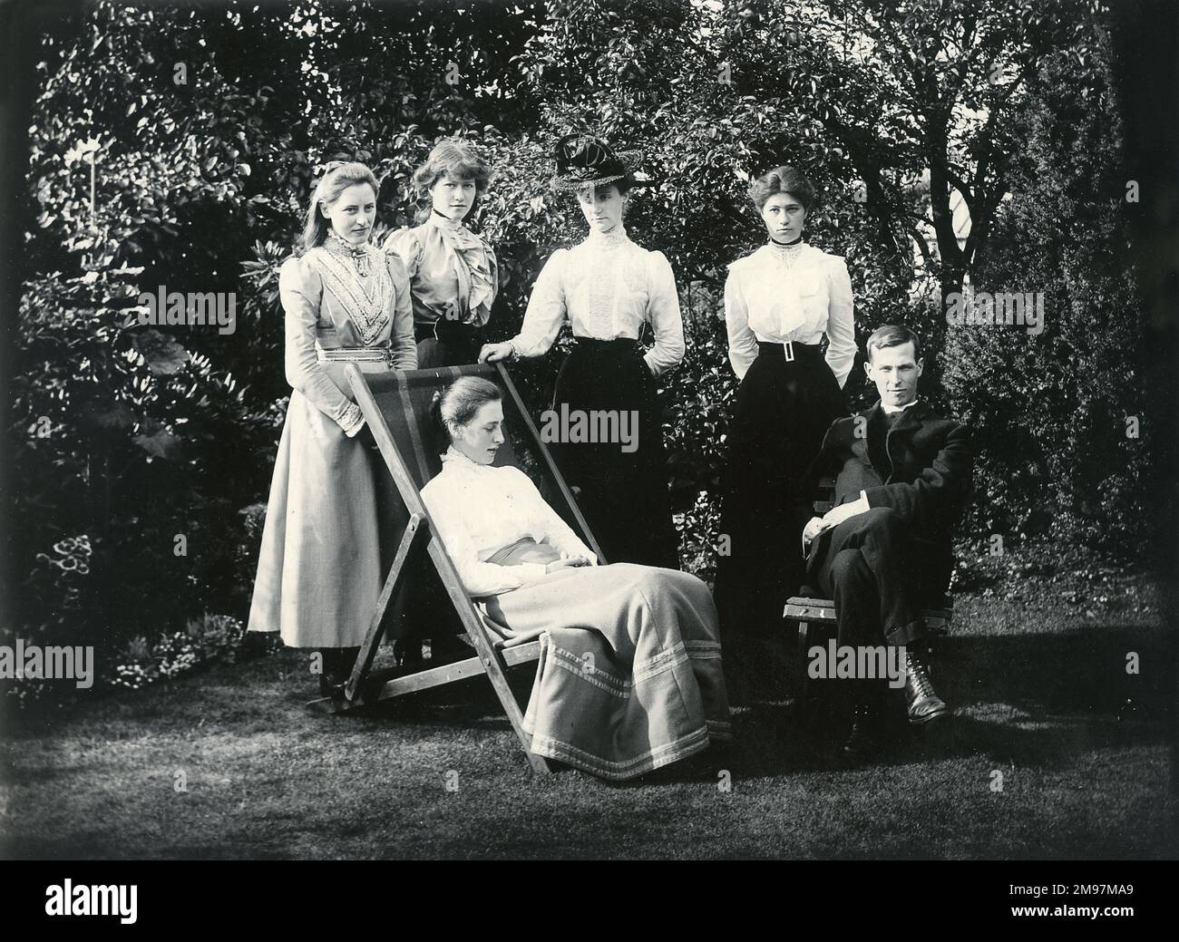 Eine Gruppe von Menschen, darunter ein Geistlicher, in einem Garten. Stockfoto