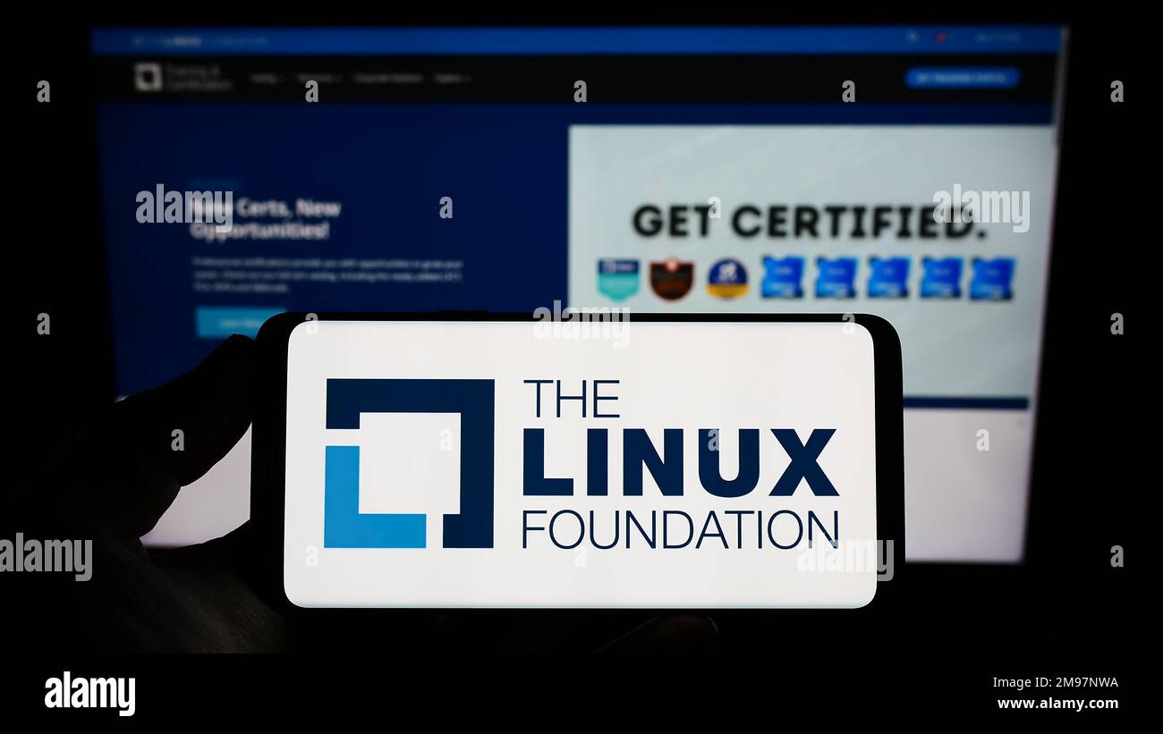 Person, die ein Smartphone mit dem Logo des Technologiekonsortiums Linux Foundation auf dem Bildschirm vor der Website hält. Konzentrieren Sie sich auf das Display des Telefons. Stockfoto