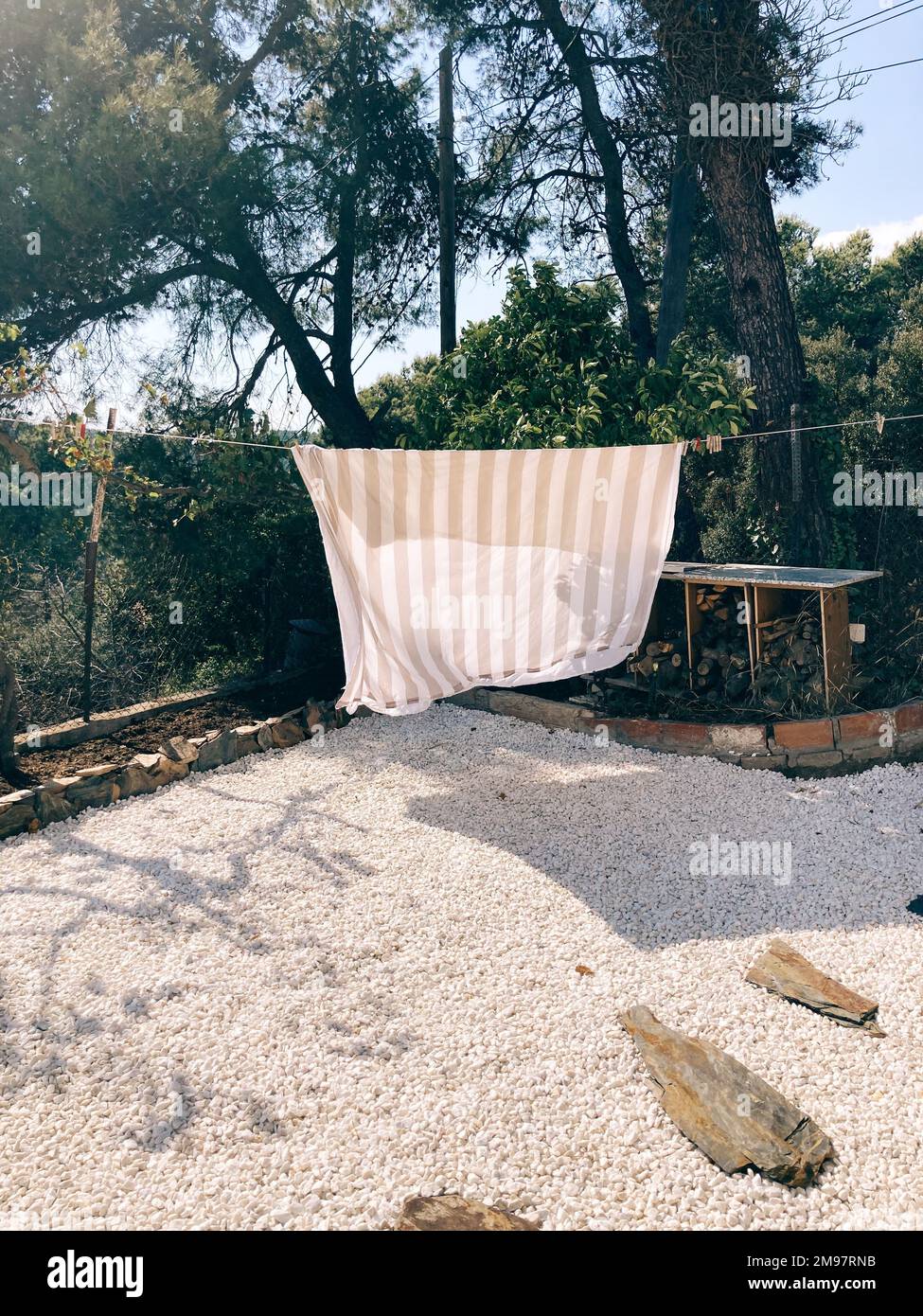 Bettlaken hängen an einer Wäscheleine in einem Garten, der in der Sommersonne trocknet, Barcelona, Spanien Stockfoto