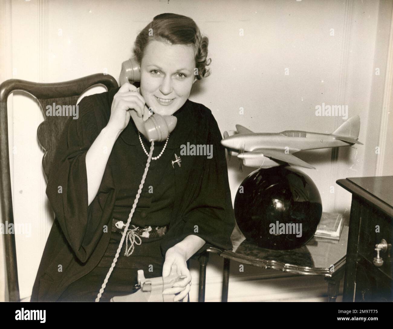 C.W.A. Scotts zweite Frau, Greta, erhielt Glückwunschbotschaften nach seinem Sieg im Schlesinger-Portsmouth-Johannesburg-Rennen. 1. Oktober 1936. Sie steht neben einem Modell des de Havilland DH88 Comet Racer, bei dem Scott 1934 das MacRobertson London to Melborne Air Race gewann. Stockfoto