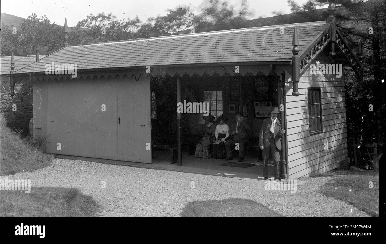 Tennispavillon in Moffat, Schottland. Drei Personen im Gebäude ruhten im Schatten, während ein Freund des Fotografen kein Geheimnis daraus macht, dass er heiß und durstig ist (oder dass er eine sichtbare Reaktion darauf zeigt, einige der lokalen Mineralquellen für den Moffat Hydro auszuprobieren!!). Stockfoto