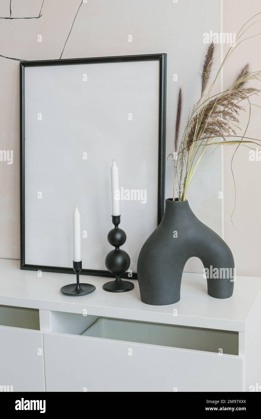 Moderne Keramikvase mit zwei Kerzenleuchtern und einem leeren Bilderrahmen auf einem Sideboard Stockfoto Moderne Keramikvase mit zwei Kerzenleuchtern und einem leeren Bilderrahmen auf einem Sideboard Stockfoto
