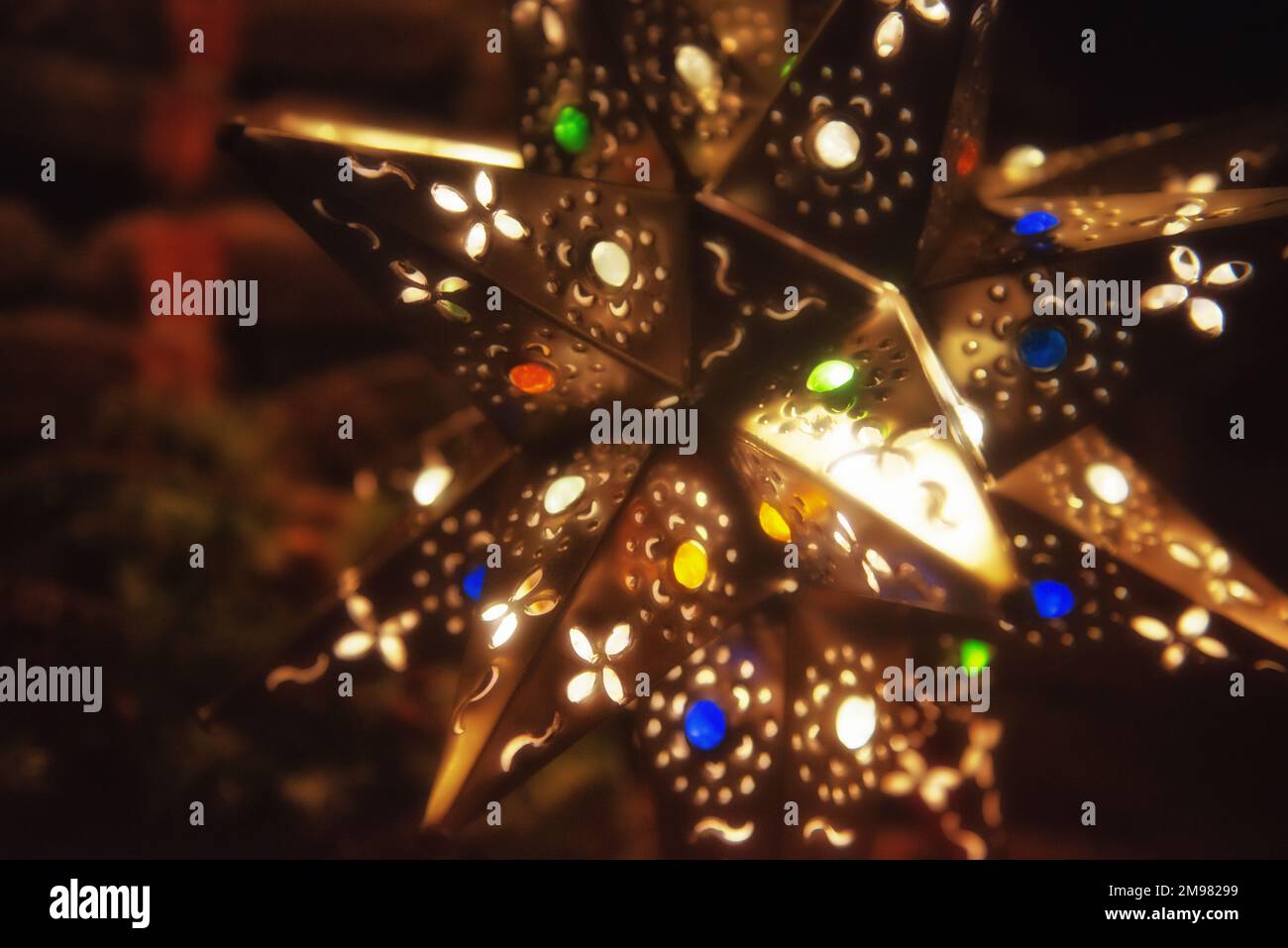 Nahaufnahme eines beleuchteten Weihnachtssternornments, das an einem Weihnachtsbaum hängt Stockfoto