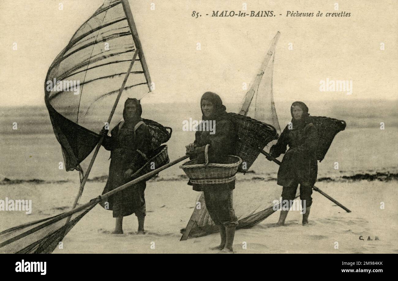 Drei Fischerinnen stehen am französischen Strand von Malo-les-Bains und halten Netze und Körbe, um Garnelen zu sammeln. Stockfoto