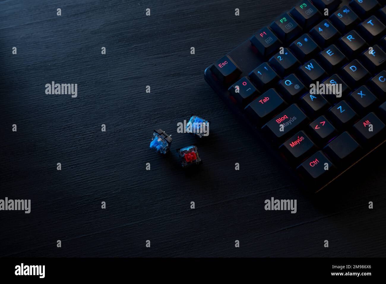 Schwarzer Holzschreibtisch mit Gamer-Tastatur und farbigen Schaltern. Stockfoto