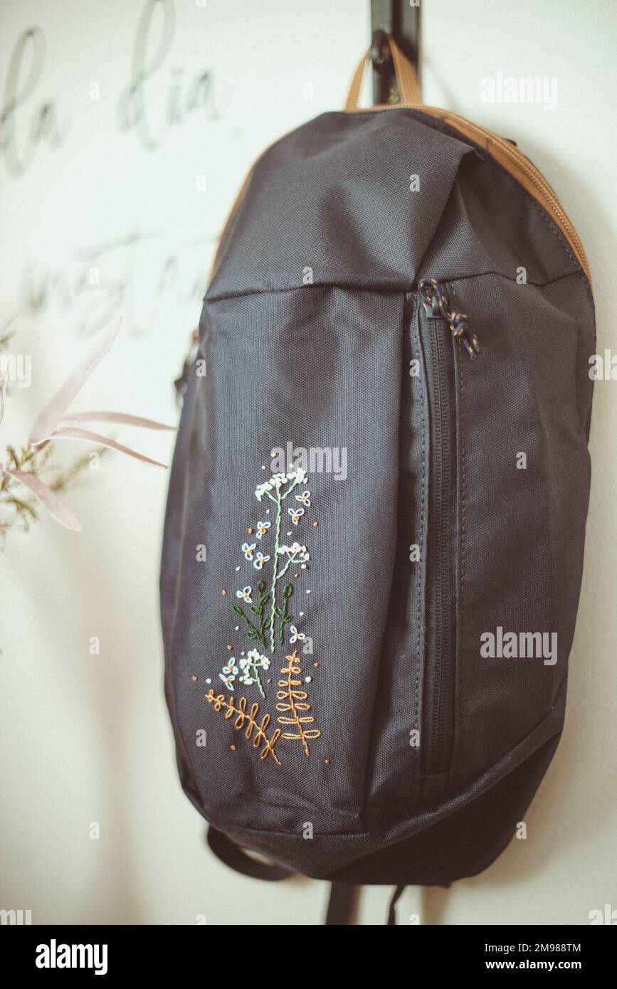 Nahaufnahme eines von Hand bestickten grauen Rucksacks, der an der Wand hängt Stockfoto