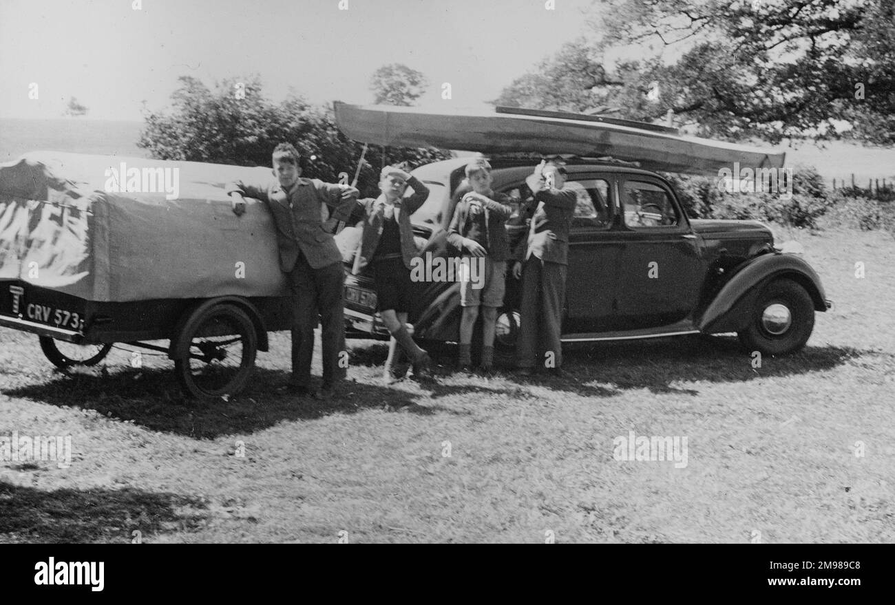 Camping mit Auto, Boot und Wohnwagen, und vier Jungs, die für die Kamera posieren. Stockfoto