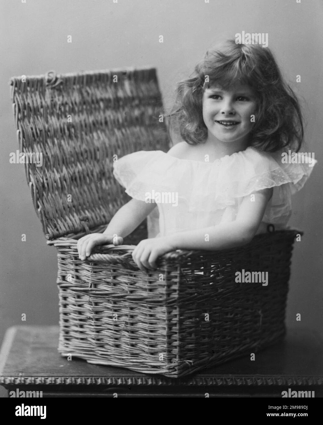 Ein junges Mädchen in einem Korb. Stockfoto