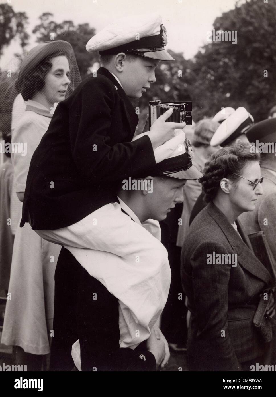 Marinekadett mit Kamera in einer Gruppe von Zuschauern. Stockfoto