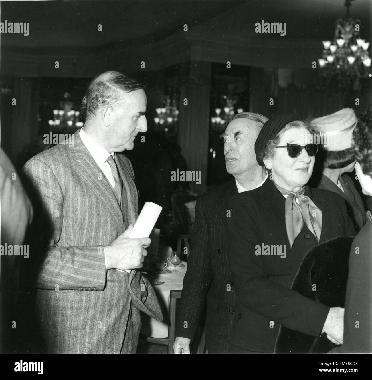 Von links: Sir Sydney Camm hört Captain Laurence Pritchard und Mrs. Pritchard, die beim 94.-Jubiläumsessen im Dorchester Hotel, London, am 12. Januar 1960 eine dunkle Brille gegen die Taschenlampen trugen. Stockfoto